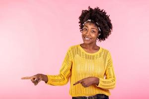 orizzontale tiro lieta buio spellato femmina con afro taglio di capelli, punti sinistra con tutti e due prua, testa dita, Spettacoli vuoto spazio per il tuo promozione, isolato al di sopra di rosa sfondo. le persone, annuncio pubblicitario concetto foto