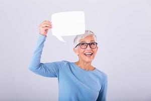 allegro maturo donna Tenere discorso bolla cartello al di sopra di sua testa e sorridente. contento anziano signora con discorso bolla bandiera foto