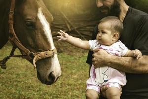 vicino su di bambino ragazza con papà toccante un' cavalla. foto