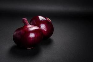 fresco crudo rosso cipolla su buio strutturato calcestruzzo sfondo foto