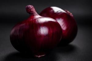 fresco crudo rosso cipolla su buio strutturato calcestruzzo sfondo foto