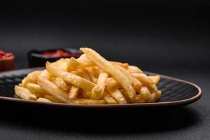 delizioso croccante francese patatine fritte con sale e spezie su un' buio calcestruzzo sfondo foto