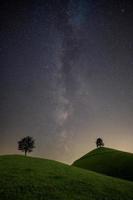 Due colline con un' albero su ogni collina, il latteo modo può essere visto nel il cielo foto