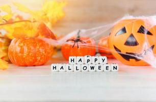 Halloween sfondo arancia con parola blocchi contento Halloween decorazioni e zucca Jack o lanterna divertente spaventoso ragno ragnatela e nero ragno su bianca di legno tavolo contento vacanza foto