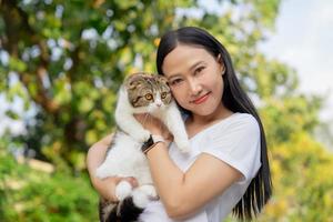 asiatico donna Tenere un' gatto a il parco foto