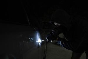 uomo nel nero provando per rubare un' macchina. auto furto concetto. foto