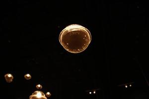 sfocatura bokeh circo tubo lampada appendere a partire dal soffitto nel buio camera piace lucciola foto