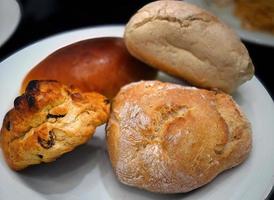 vicino su vario di fresco al forno pane, forno, Pasticcino pronto per mangiare per prima colazione su bianca piatto foto