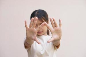 asiatico donna utilizzando sua mani per proteggere contro arrivo pericoli foto