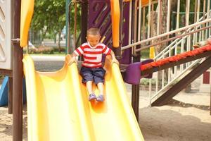 ragazzo giocando nel il terreno di gioco nel il parco foto