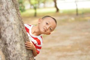 un' ragazzo nasconde dietro a un' albero così il suo madre non posso vedere foto