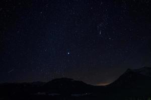 bellissimo cielo con stelle raggiante al di sopra di silhouette paesaggio a notte foto