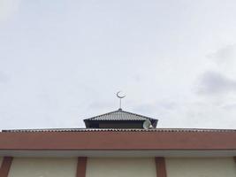 moschea cupola con metà Luna simbolo contro blu chiaro cielo sfondo, copia spazio foto
