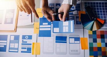 vicino su UX sviluppatore e ui progettista di brainstorming di mobile App interfaccia wireframe design su tavolo con cliente breve e colore codice a moderno ufficio.creativo digitale sviluppo agenzia foto