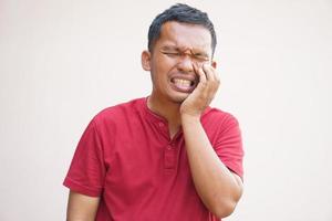 asiatico uomo soffre a partire dal mal di denti a partire dal cibo scarti foto