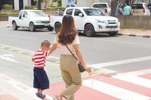 madre prende sua bambino per camminare attraverso il strada. foto