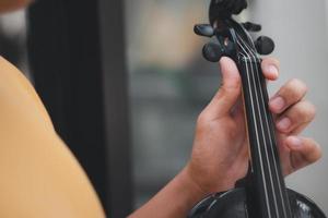 un ragazzino asiatico che suona e pratica lo strumento a corda musicale del violino contro in casa, concetto di educazione musicale, ispirazione, studente di scuola d'arte per adolescenti. foto