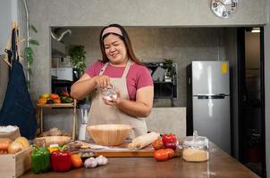 ritratto di obeso donna cucinando Pizza nel il cucina, crudo Pizza nel il mani di un' casalinga. fatti in casa Pizza cucinando nel il cucina a casa. apprendimento Come per rendere delizioso Pizza cena pranzo foto