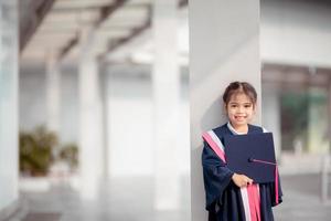 contento asiatico ragazze nel la laurea abiti su loro la laurea giorno a scuola.diploma concetto con copia spazio. foto