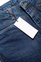 modello di un' bianca carta di un' capi di abbigliamento etichetta su denim i pantaloni foto