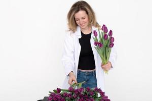 carino ragazza nel un' camicia raccoglie un' mazzo di viola tulipani per un' regalo per sua madre foto