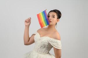 giovane asiatico bellissimo sposa con arcobaleno bandiera su bianca sfondo foto