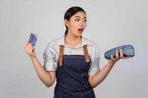 ritratto di giovane asiatico donna nel cameriera uniforme posa con credito carta foto