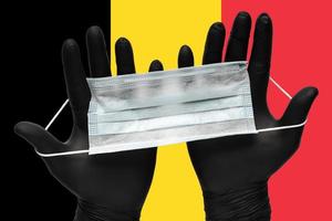 medico detiene medico viso maschera nel mani nel nero guanti su sfondo colori bandiera di Belgio. concetto pandemia assicurazione coronavirus foto