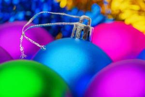 luminosa blu Natale palla nel selettivo sfocato nel primo piano, circondato di sfocato colorato vacanza palle per decorare Natale albero foto