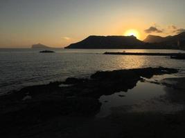 spiaggia mediterranea senza persone al tramonto a calpe, alicante foto