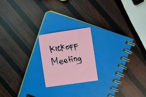 kickoff meeting scritto su una nota adesiva isolato su un tavolo di legno foto