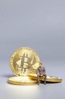 imprenditore in miniatura seduto su monete bitcoin, futuro concetto di investimento