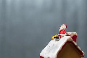 Babbo Natale in miniatura seduto su un tetto, leggenda natalizia e concetto di buone feste foto