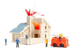 vigili del fuoco in miniatura che si prendono cura di un'emergenza incendio in una casa di legno foto