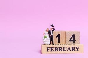 sposa e sposo in miniatura su uno sfondo rosa, il giorno di San Valentino e il concetto di matrimonio foto