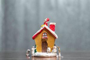 persone in miniatura che dipingono una casa e Babbo Natale seduto sul tetto, buon Natale e concetto di buone feste foto