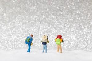 Backpackers in miniatura camminando su uno sfondo di neve, concetto di inverno foto