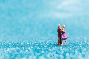 coppia in miniatura che balla su sfondo blu glitter, concetto di san valentino foto