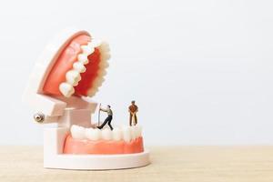 lavoratori in miniatura che riparano un dente, assistenza sanitaria e concetto medico foto