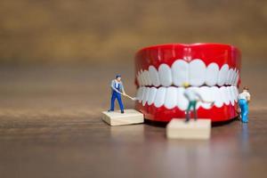 lavoratori in miniatura che riparano un dente, assistenza sanitaria e concetto medico foto