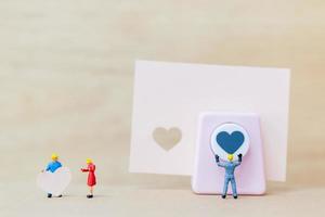 coppia in miniatura con un cuore di carta su fondo in legno, concetto di San Valentino