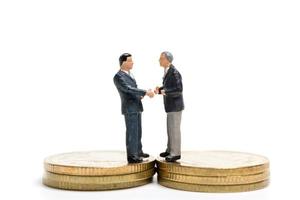 uomini d'affari in miniatura in piedi su una pila di monete, denaro e concetto finanziario foto
