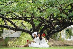 due donne vestite di bianco e con in mano fiori foto