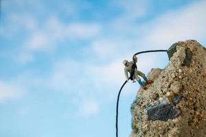 escursionisti in miniatura che si arrampicano su una roccia, sport e concetto di tempo libero foto