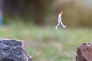 persone in miniatura in esecuzione su una scogliera rocciosa con sfondo della natura, concetto di salute e stile di vita foto