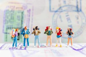 viaggiatori in miniatura con zaini che camminano su un passaporto, viaggi e concetto di avventura