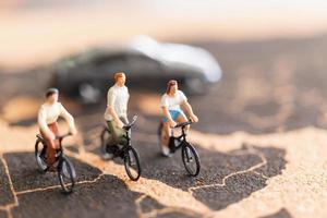 viaggiatori in miniatura con biciclette su uno sfondo di mappa del mondo foto