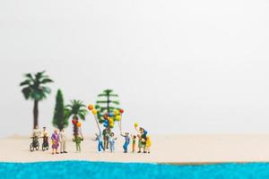 persone in miniatura che si godono le vacanze estive sulla spiaggia foto