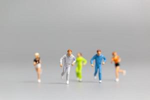 persone in miniatura che corrono su uno sfondo grigio foto