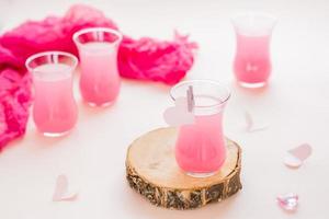 rosa cocktail nel bicchieri e carta cuori su un' rosa sfondo. bevande per Gli amanti foto